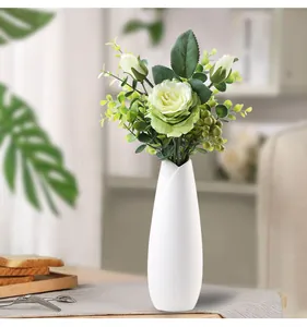 Elegant modern white ceramic vase featuring green artificial roses on a dining table