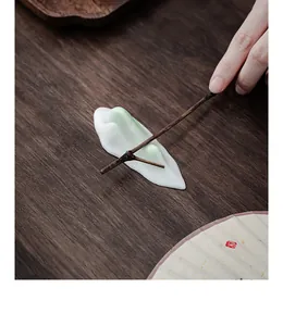 Close-up of a minimalist white and green ceramic Zen mountain ornament on dark wood