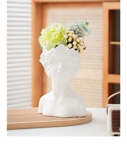 Minimalist white ceramic human bust vase with elegant floral arrangement in home setting
