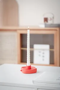 Détail d'un bougeoir pomme en céramique rouge avec bougie torsadée blanche décor nordique
