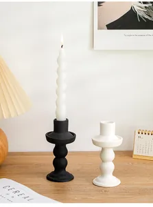 Black and white ceramic candlestick holders on a wooden table with a burning candle