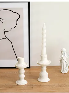 Close-up detail of Nordic white speckled ceramic candlesticks on a wooden table