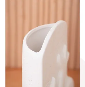 Close-up detail of a white speckled ceramic vase with a minimalist irregular rim