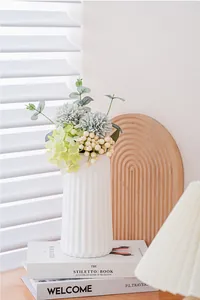 Gros plan d'un élégant vase en céramique cannelé blanc avec de fausses fleurs
