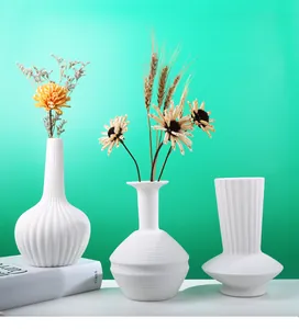 Detailed view of three minimalist white ceramic vases with elegant linear textures