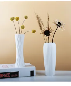 Detail showing two minimalist white textured ceramic vases with dried flower arrangement
