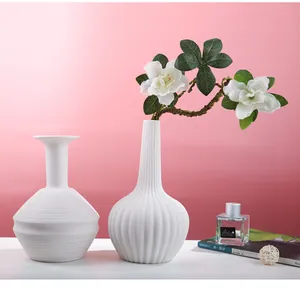 Detailed view of minimalist white ceramic vases with elegant linear textures for home decor