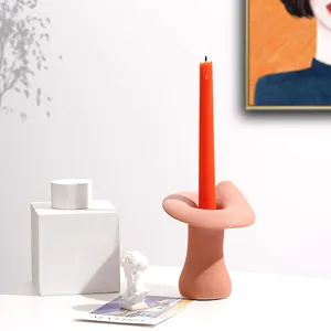 Close-up van een roze keramische kandelaar op een artistiek gedekte tafel