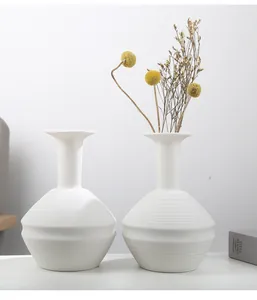 Detailed macro view of minimalist white ceramic vases with ribbed and faceted textures.
