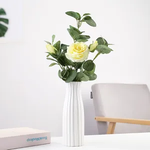 Modern white ribbed ceramic vase with artificial yellow rose arrangement for home decor