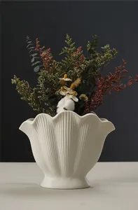 Detailed view of a minimalist white ceramic shell vase with dried flower decor
