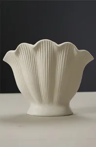 Close-up detail of a cream white fluted ceramic shell vase with scalloped edges
