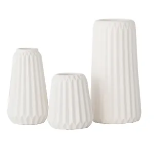 Ensemble de trois vases en céramique blanche avec motif géométrique sur fond blanc.