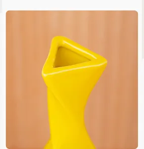 Detailed view of a vibrant yellow ceramic vase featuring a unique triangular opening.