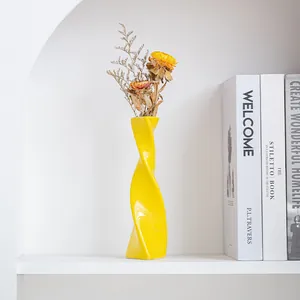 Modern twisted yellow ceramic vase for home decor displayed on a minimalist white shelf