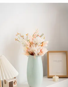 Vista ravvicinata di un elegante vaso di ceramica verde chiaro con fiori artificiali di pesca