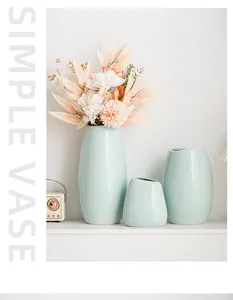 Set di tre vasi in ceramica verde chiaro con fiori artificiali su mensola