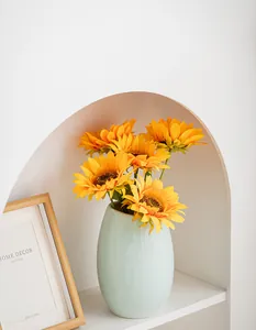 Moderno vaso in ceramica verde menta con girasoli gialli in una nicchia bianca ad arco