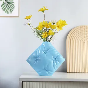 Vase créatif en céramique bleu ciel avec texture matelassée sur une table blanche