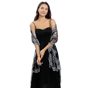 Detail of black sheer shawl with silver embroidery and tassels worn with a dress