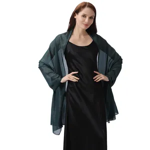 Modelo con un chal de fiesta verde oscuro metalizado sobre un vestido de satén negro