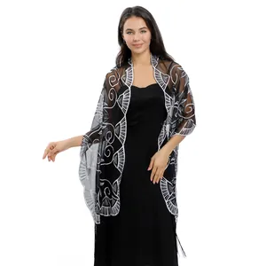 Detail view of sheer black shawl featuring intricate silver sequin embroidery and elegant tassels