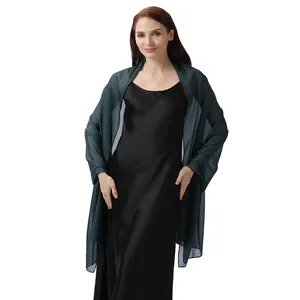 Modelo con un chal de noche verde oscuro transparente sobre un vestido de satén