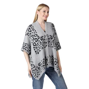 Detailed view of a soft grey leopard print knitted poncho on a model in white background