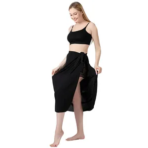 Ganzkörperansicht eines Models in einem schwarzen Wickel-Sarong-Strandrock-Cover-up.