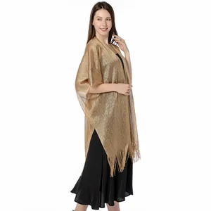 Detailed side view of an elegant gold metallic fringe shawl worn over a black dress