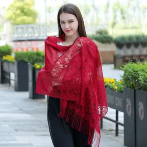 Elegant red lace shawl scarf with floral pattern and tassels worn by a model in garden