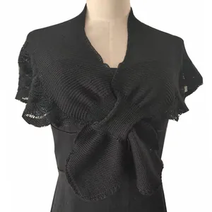 Detail view of black knitted wrap shawl with elegant front twist on mannequin