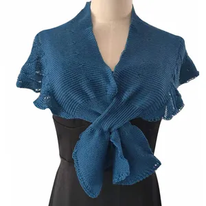 Detail of blue knitted shrug shawl wrapped over a black evening dress on mannequin