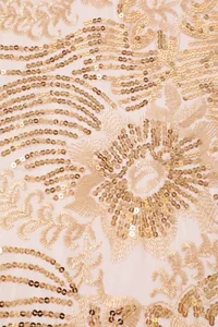 Macro detail of sunflower sequin embroidery on champagne gold lace fabric for evening shawl