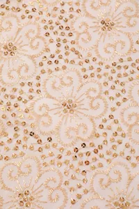 Close-up detail of elegant gold sequin embroidery and floral patterns on mesh fabric
