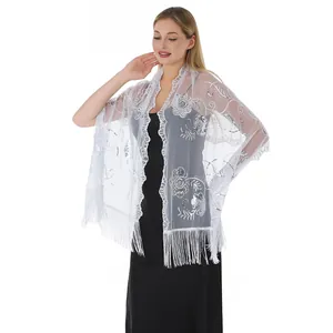 Detail view of white sequin floral embroidery and fringe tassels on a mesh wedding shawl