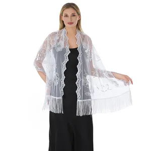 Detailed view of white floral sequin embroidery and delicate fringe trim on shawl