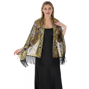 Close-up of sun flower sequin embroidery and tassels on elegant black and gold evening shawl.