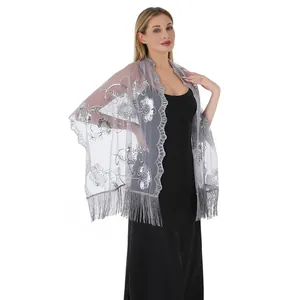Detail of silver sequin floral embroidery and fringe tassels on grey mesh shawl wrap.