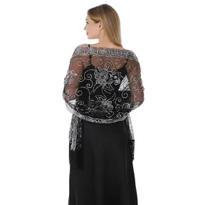 Vue arrière d'un châle en maille noire avec fleurs en paillettes argentées et franges.