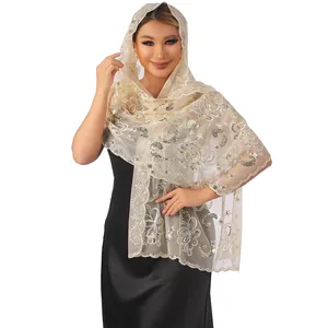 Close-up of elegant beige lace shawl with gold sequins embroidered floral pattern