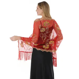Detail showing the back of a red shawl with intricate gold floral sequin embroidery and tassels