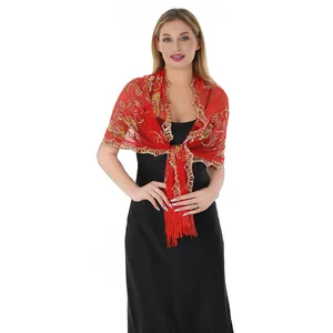 Detail view of a luxury red evening shawl with gold embroidery and tassels worn by a model.