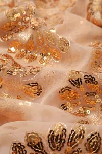 Dettaglio ravvicinato di tessuto a rete beige con ricamo floreale di paillettes dorate