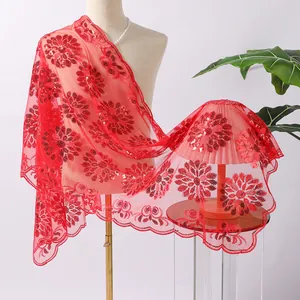 Dettaglio del ricamo floreale con paillettes rosse su un elegante scialle a rete