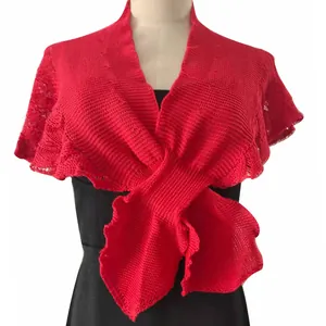 Close-up of a red knitted shawl featuring a delicate fish-tail hem and openwork texture.