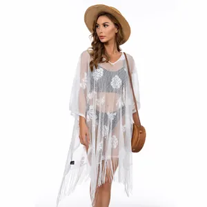 Detailed view of white floral lace beach cover-up with elegant tassel fringe hem