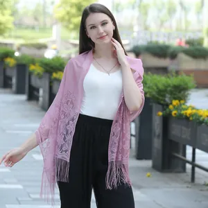 Close-up detail of a soft pink lace shawl featuring elegant floral embroidery and fringe tassels