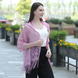 Close-up of elegant pink lace shawl with tassels worn by model outdoors