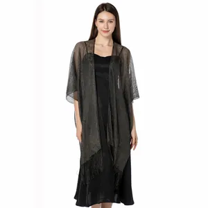Detailed shot of an elegant shimmering gold silk shawl with fringe over a black dress.